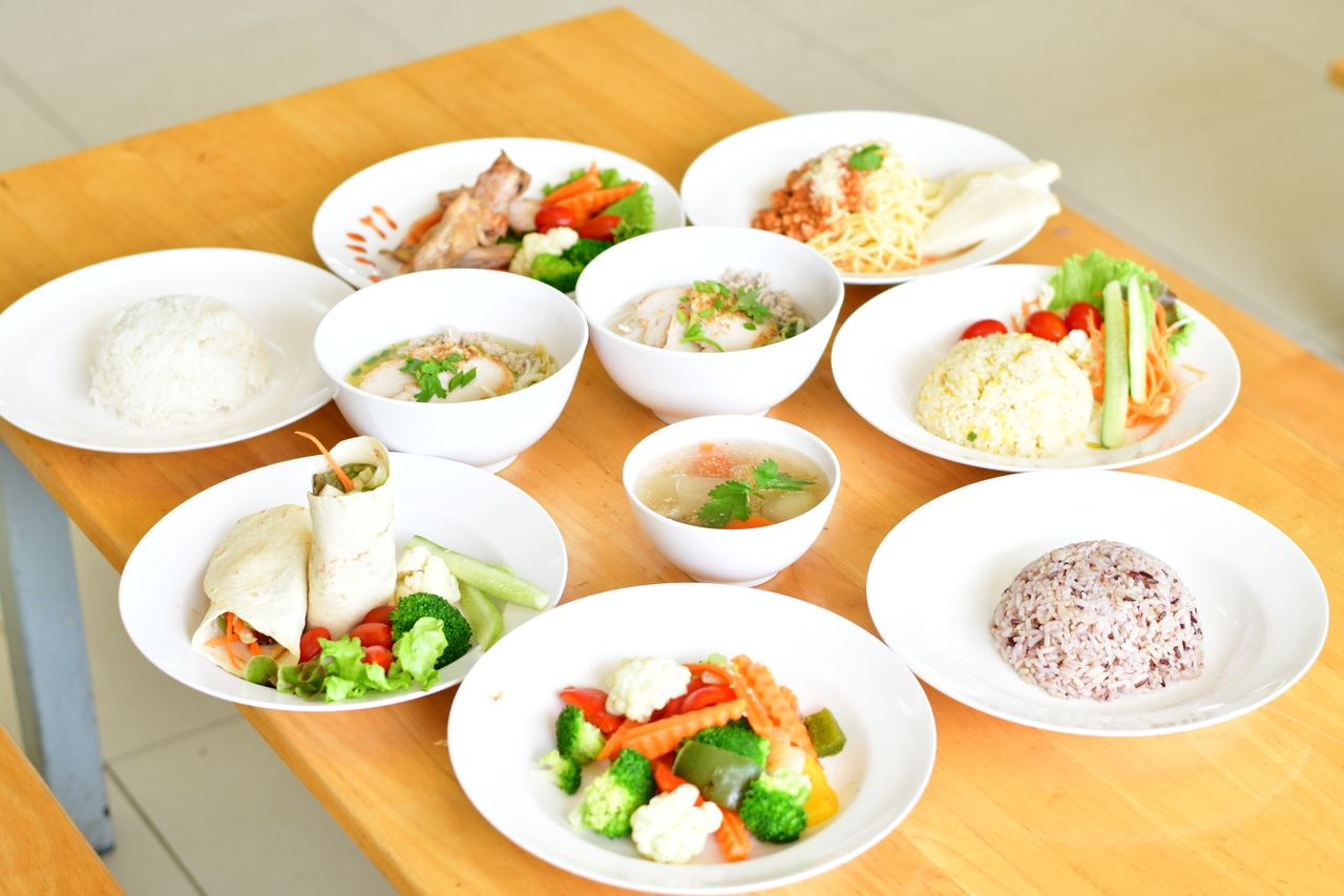 services-01 A variety of healthy dishes including rice, soup, and vegetables served on a wooden table.