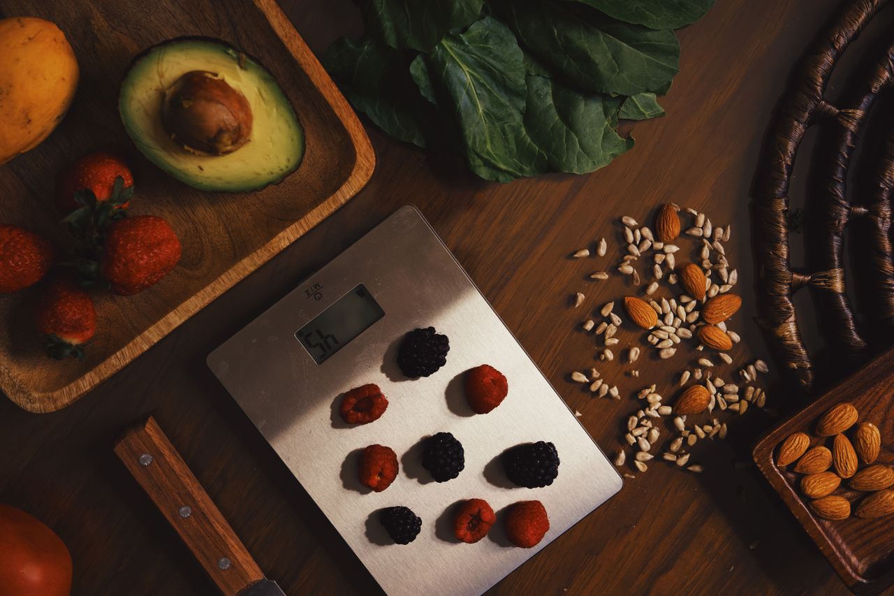 services-02 Top view of composed raw almond with seeds and avocado on table with berries on scales for cooking healthy dish